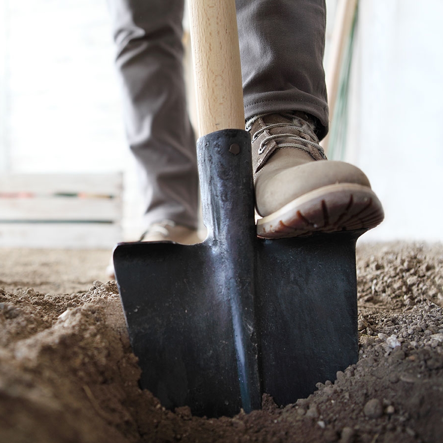 foot on a shovel in the dirt